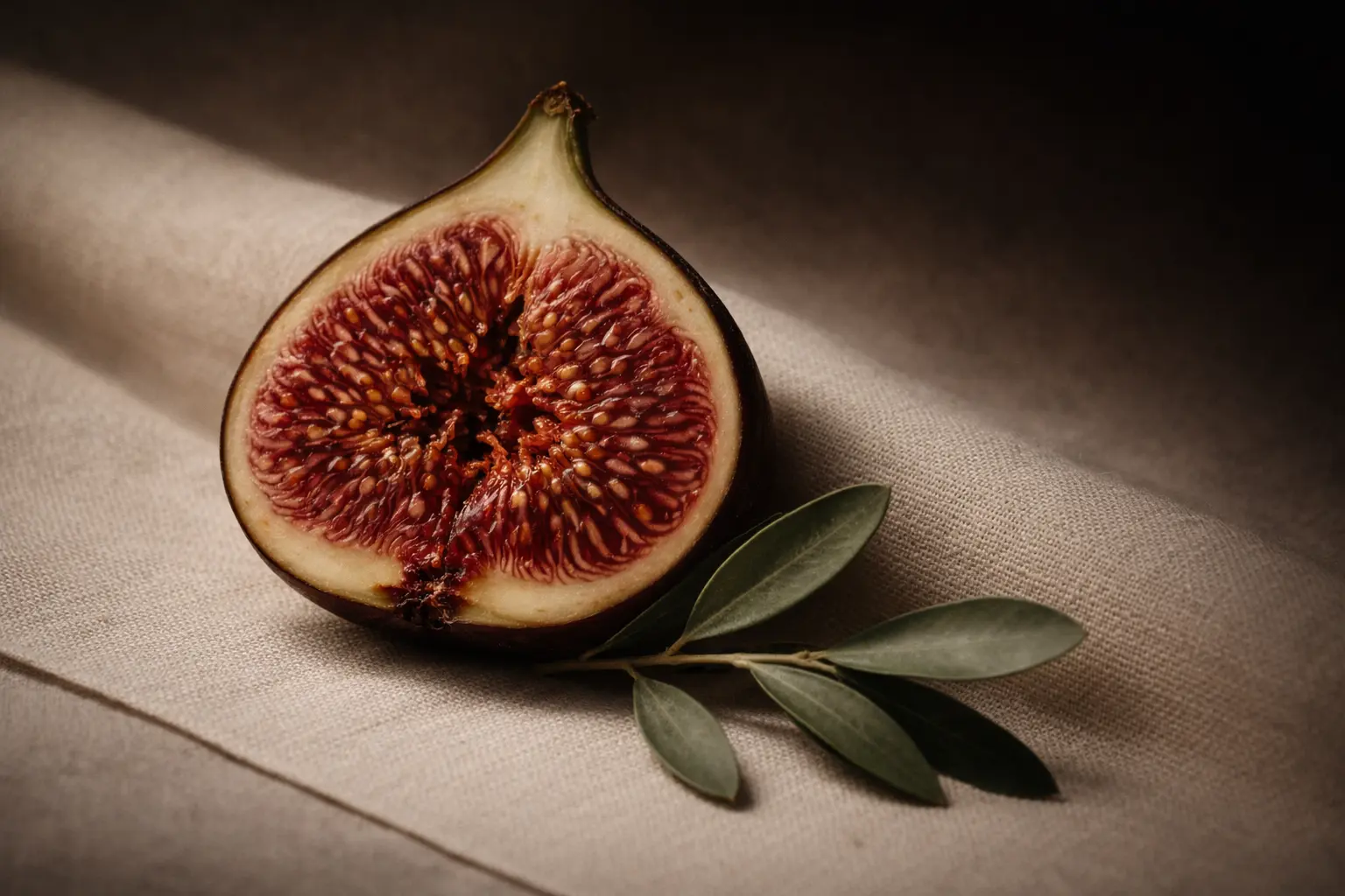 Aufgeschnittene Feige mit Olivenzweig auf hellem Leinenstoff – Blogartikel über männliche Energie bei Frauen